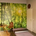 Praxisraum Behandlungsraum mit Therapieliege, Stuhl und beruhigenden Waldmotiv an der Wand
