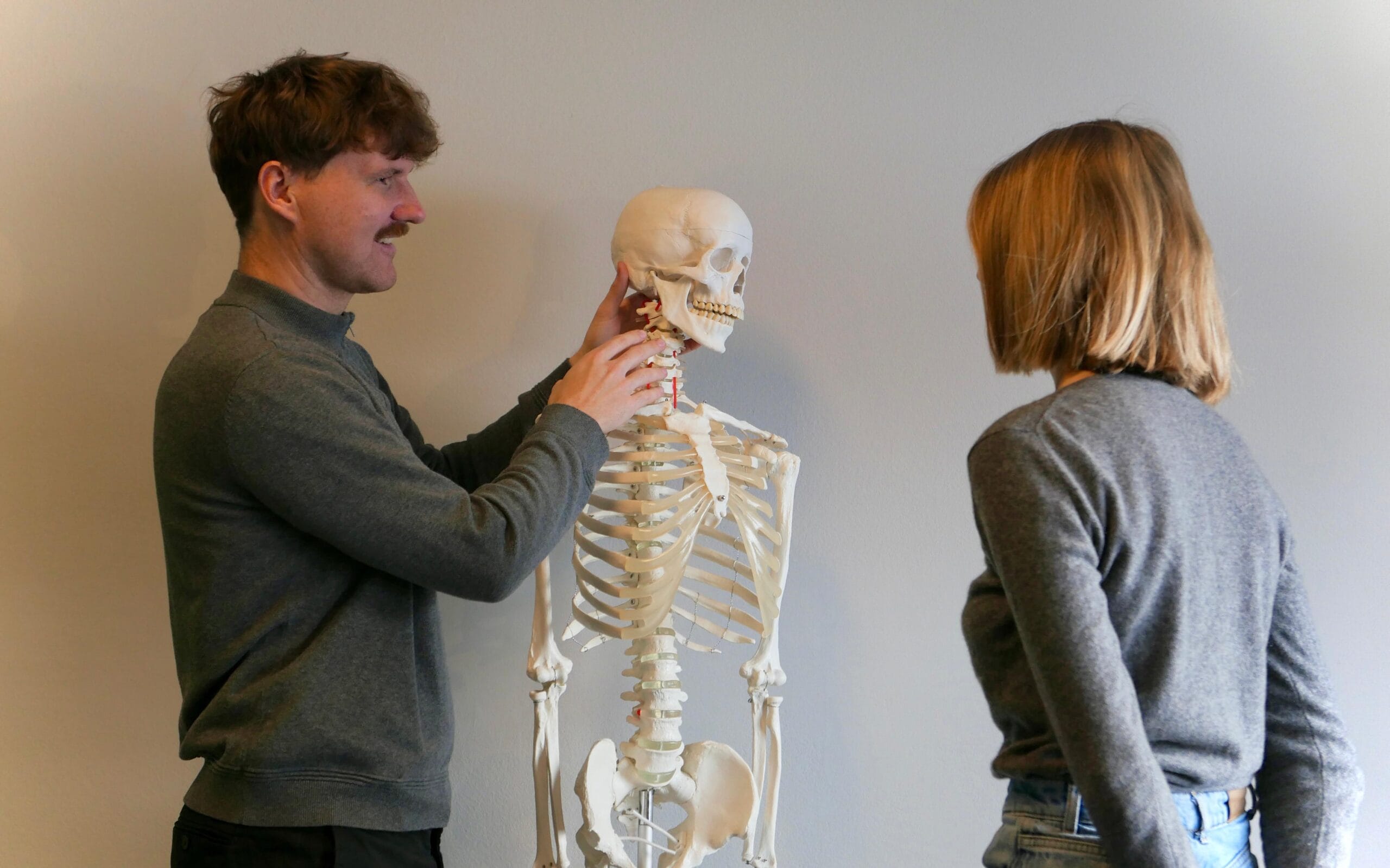 Persönliche Betreuung Therapeut erklärt an einem anatomischen Skelett im persönlichen Gespräch mit einer Kundin